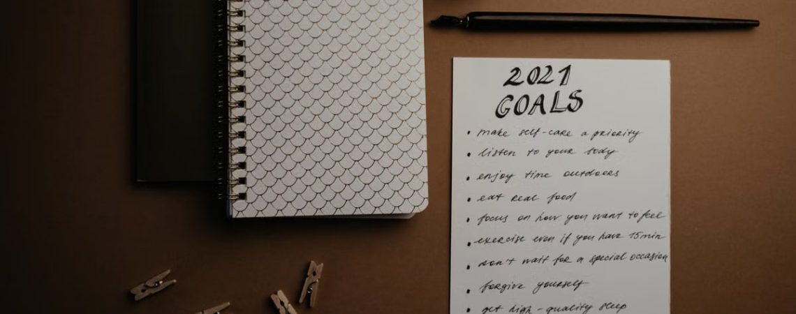 Aesthetic flatlay of notebooks and a 2021 goals list in elegant calligraphy.